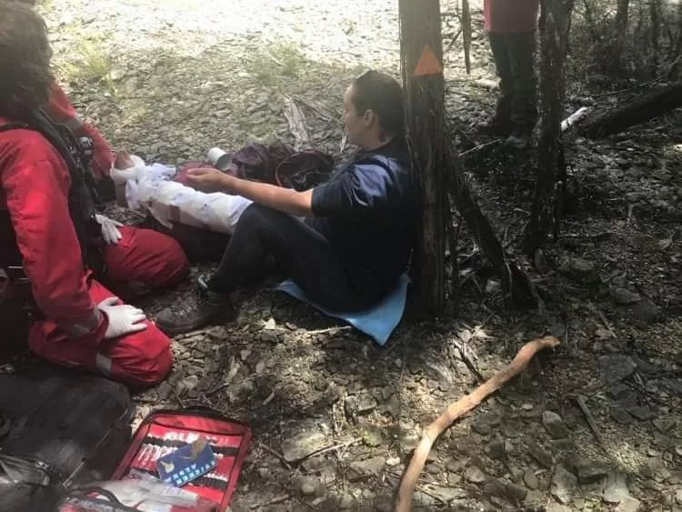 Woman lying on the ground with a paramedic attending her