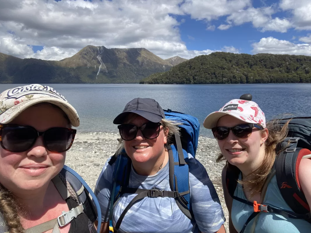 Three friends smiling at the camera with Green Lake behind them