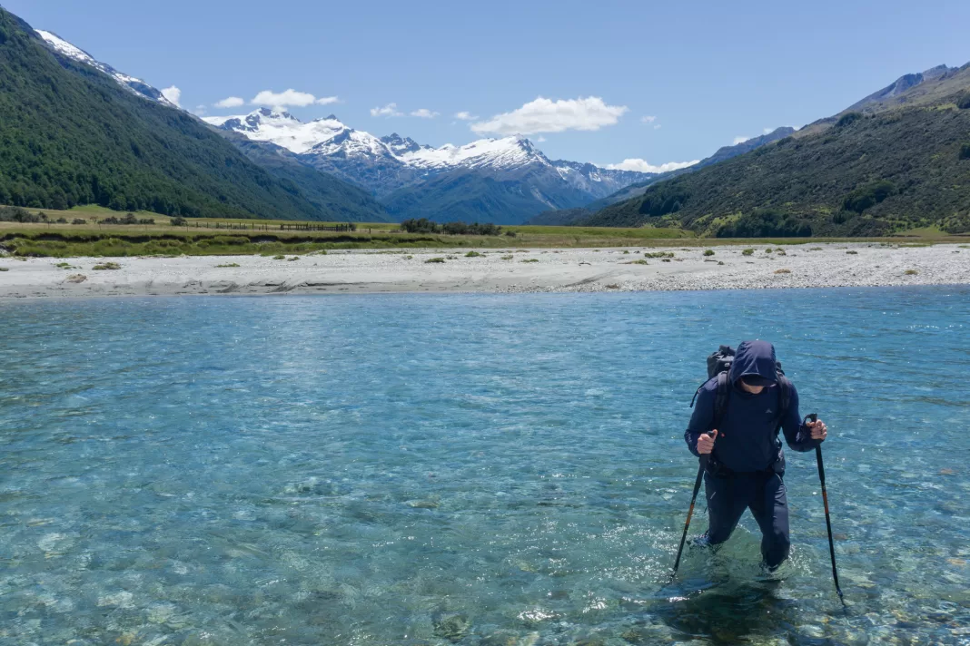 Matt crossing the Rees River with snowy Mt Clarke in the background