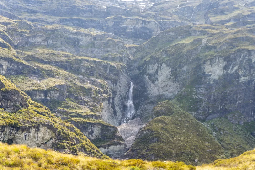 Waterfall cascading down verdant cliffs in Kea Basin