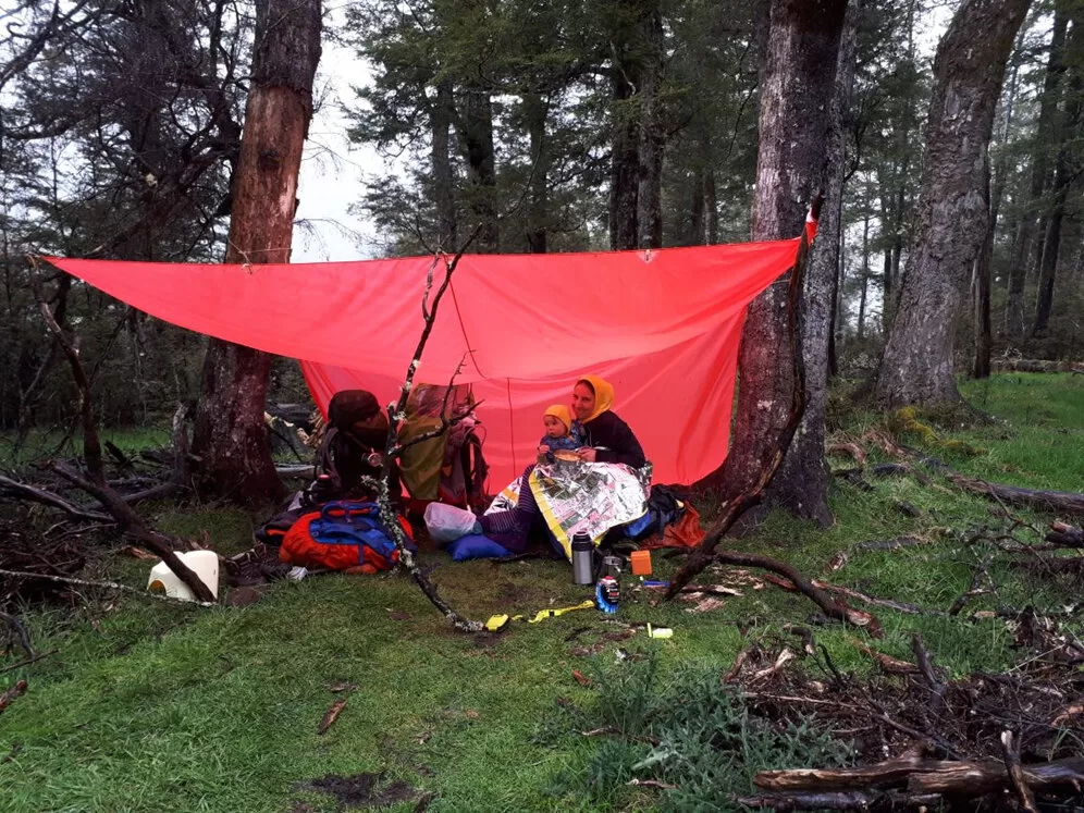 Tramper and baby sheltering under a tarpaulin shelter