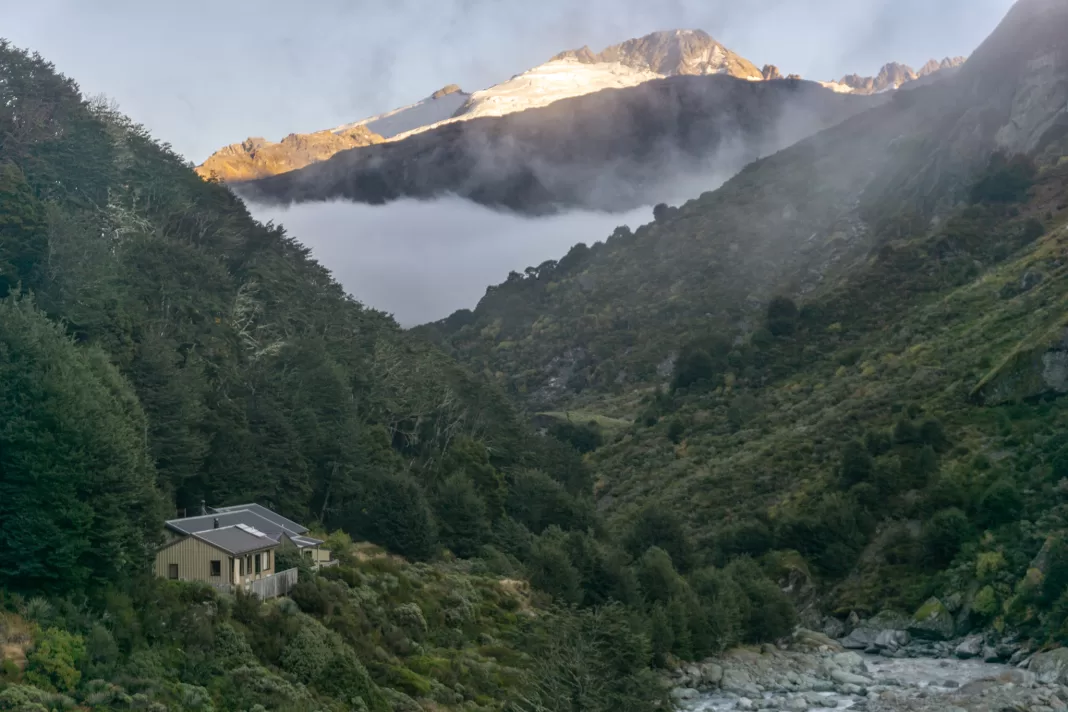 Dart Hut with sunrise lighting the mountains behind