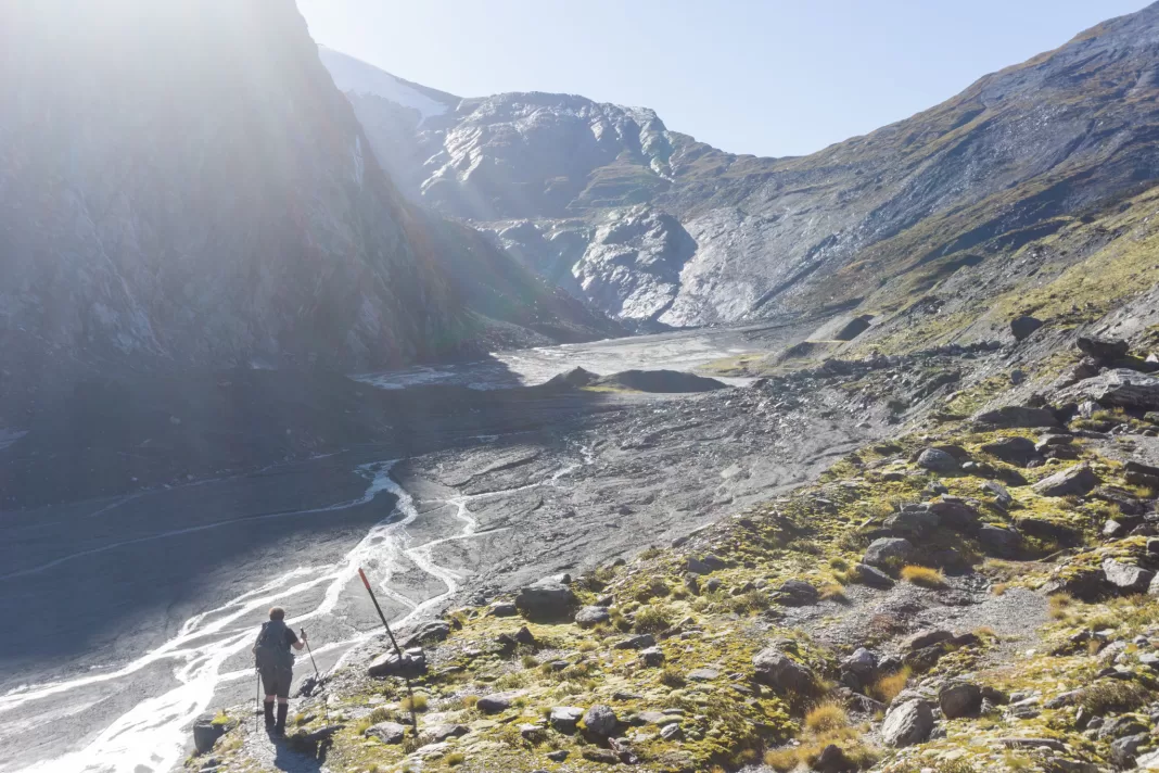 Woman walking up the Dart River with Cascade Saddle in the distance