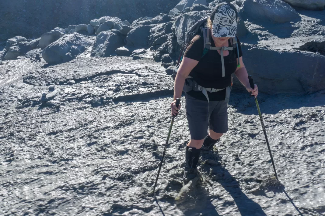 Woman crossing a muddy, fast-flowing stream
