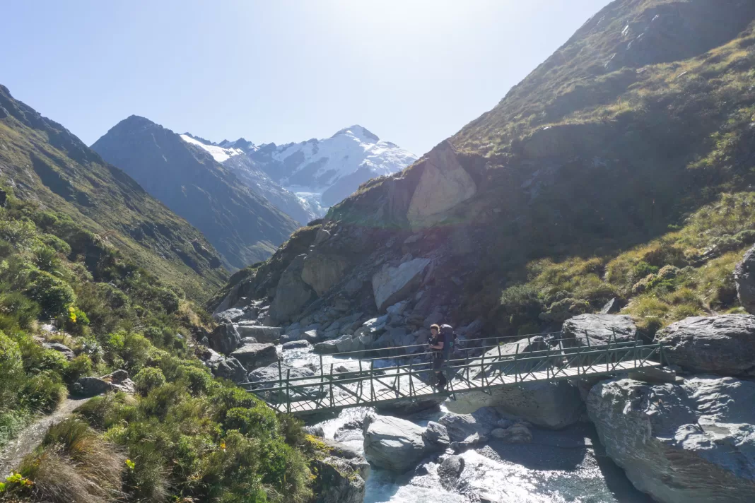 Person crossing Snowy Creek bridge on the Rees Dart Track