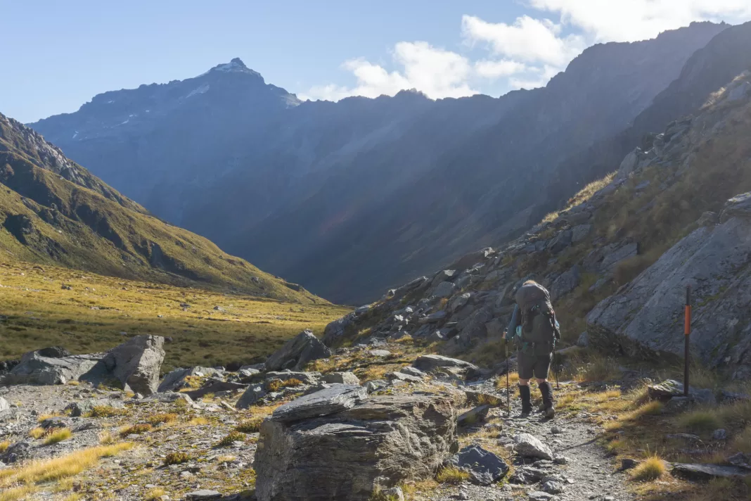 Tramper walking along the Rees Dart Track with mountains in the background