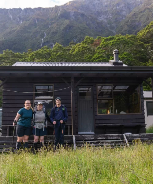 Photo of three trampers outside Top Forks Hut in Mt Aspiring National Park