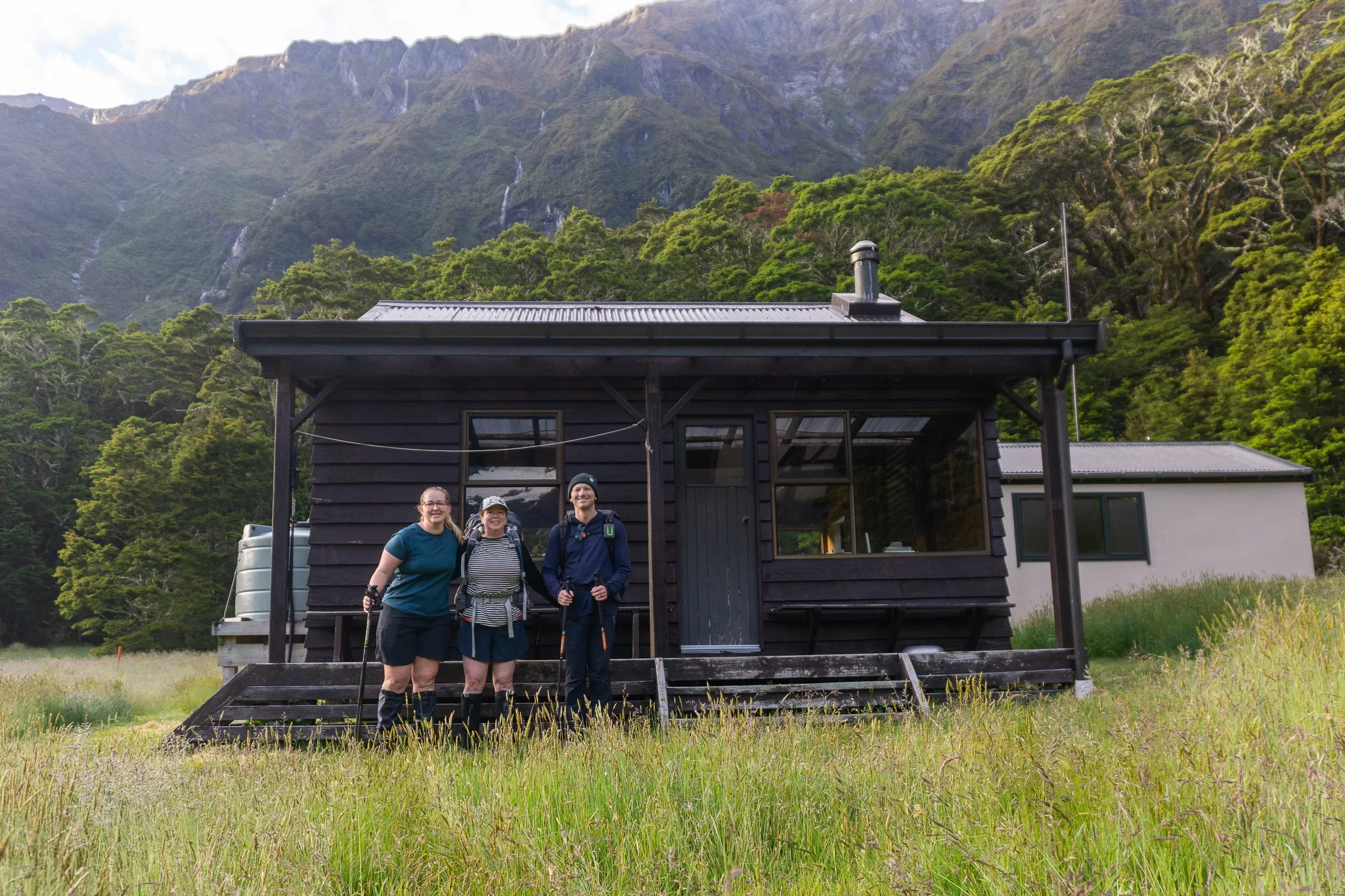 Photo of three trampers outside Top Forks Hut in Mt Aspiring National Park